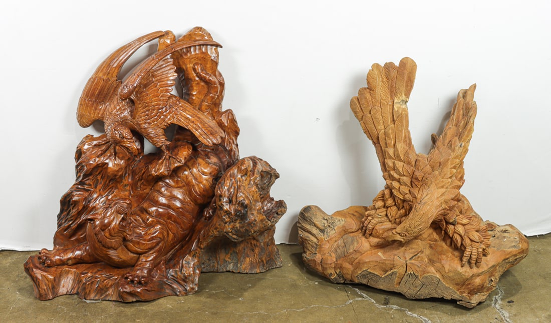 Two carved sculptures of eagles: Two carved sculptures of eagles, one depicting a scene with a roaring tiger, 36"h x 35"w x 14"d, and one depicting an eagle on a rocky summit, 34"h x 28"w x 22"d