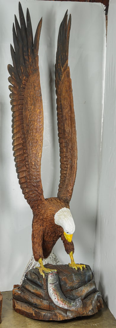 A Folk Art hand carved and paint decorated figure of a bald eagle: A Folk Art hand carved and paint decorated figure of a bald eagle, the large form depicted with a fish caught in its talons, signed 'WQA', 91"h x 27"dia (base)