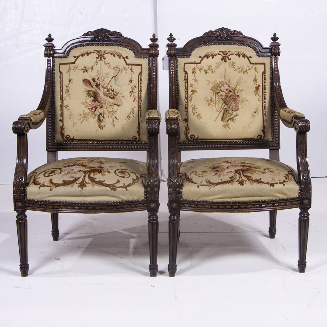 A pair of Louis XVI fauteuils, circa 1860: A pair of Louis XVI style fauteuils, circa 1860, each armchair with a carved ribbon and scroll medallion above the petit point upholstery, and rising on turned and fluted legs, 39"h x 20"w x 15.5"d