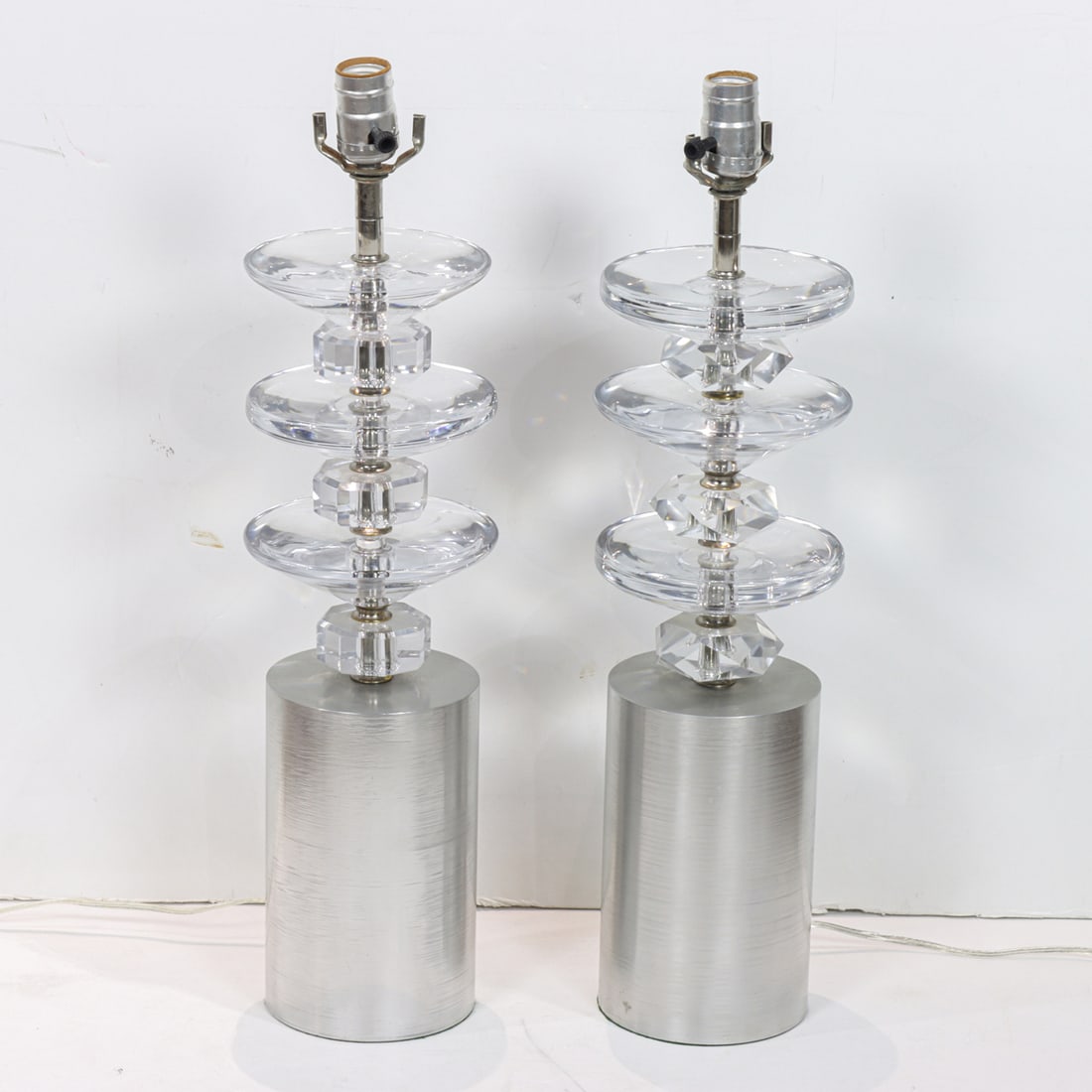 A pair of Modern brushed steel and glass table lamps: A pair of Modern brushed steel and glass table lamps, each composed of alternating glass discs on a cylindrical plinth, metal inscribed 'Kawahara, New York', 17.75"h (excluding electrical fittings)