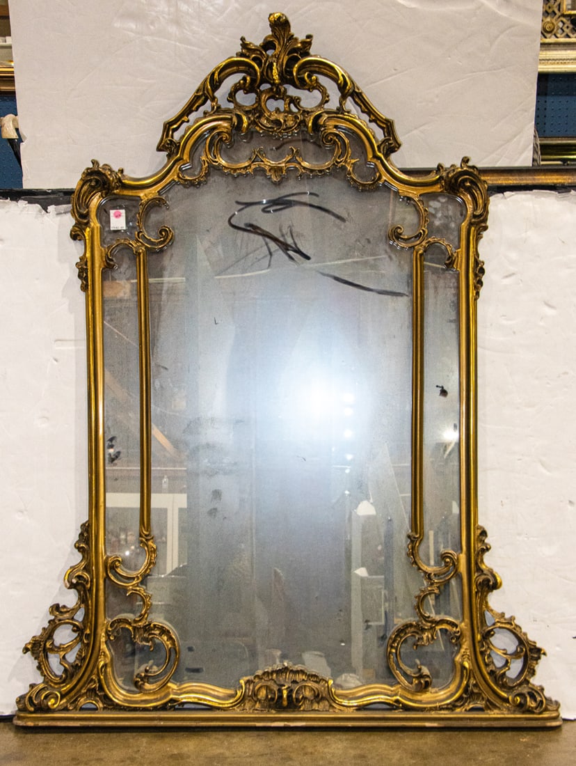 A large Rococo style giltwood mirror: A large Rococo style giltwood mirror, the framed composed of C-scrolls, 63"h x 48"w
