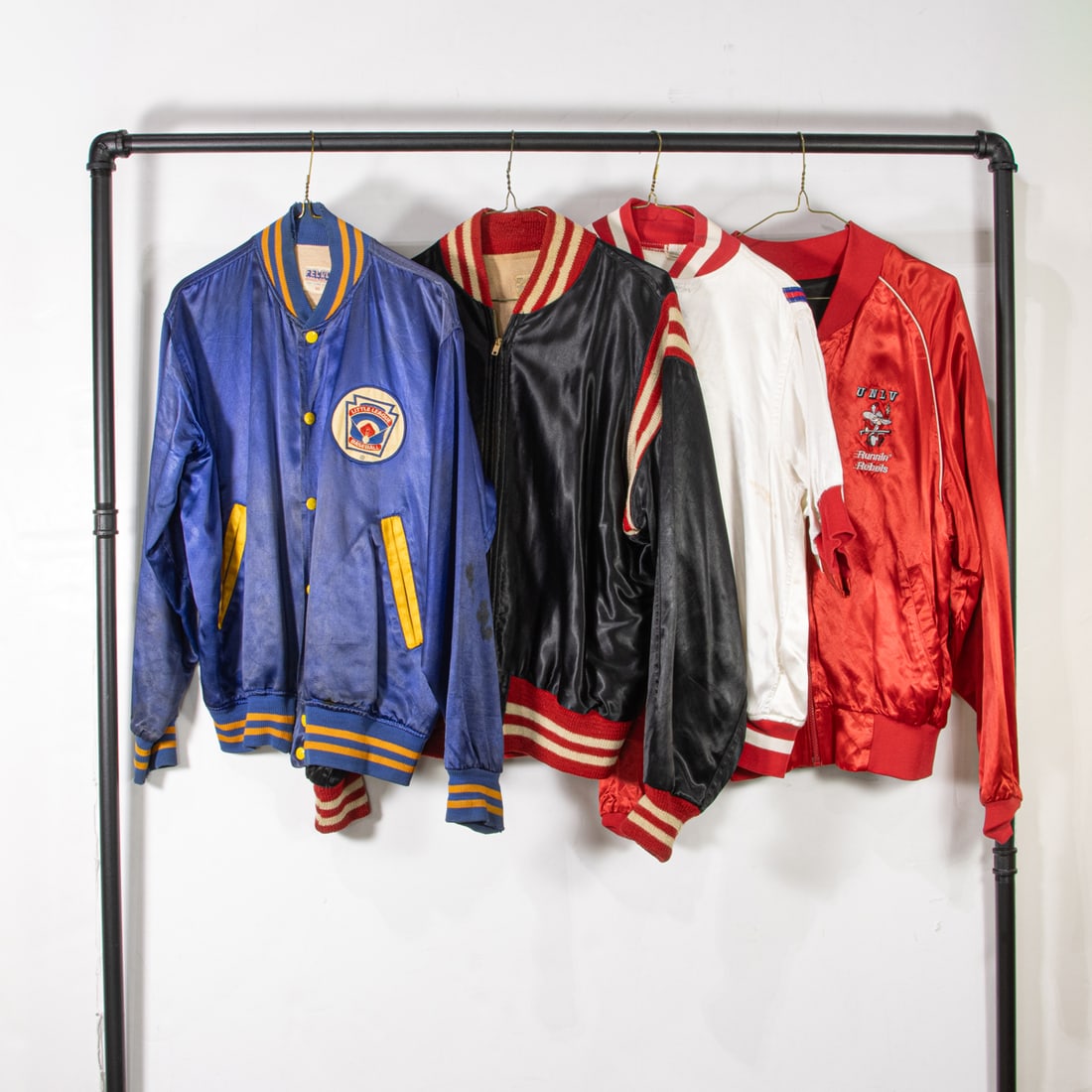 Three vintage satin jackets and one jersey: Three vintage satin jackets and one jersey, (1) white "Colts" satin jersey, (1) navy "Larkfield" size 40, (1) black "St. Demitrios" size 44, (1) reversible red and black University of Nevada Las