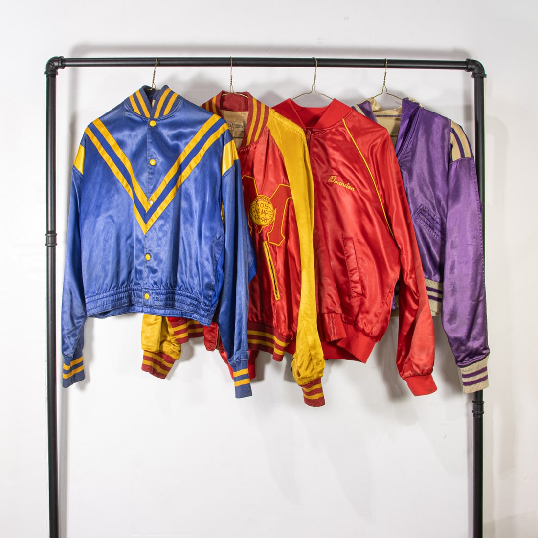 Four vintage satin jackets: Four vintage satin jackets, (1) blue and golden yellow "Sparks" size 38, (1) cardinal red and golden yellow "NewFoundland" size not labled, (1) red "North Hills Region 174" size medium, (1) purple