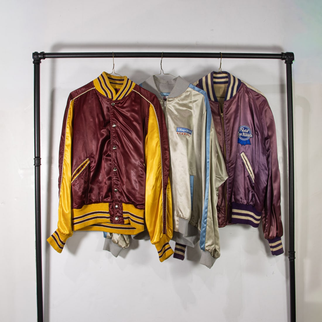 Three vintage satin jackets: Three vintage satin jackets, (1) maroon and golden yellow size not labeled, (1) light blue and silver "Disney Studios" size xlarge, (1) purple and silver "Pabst Blue Ribbon" size not labeled