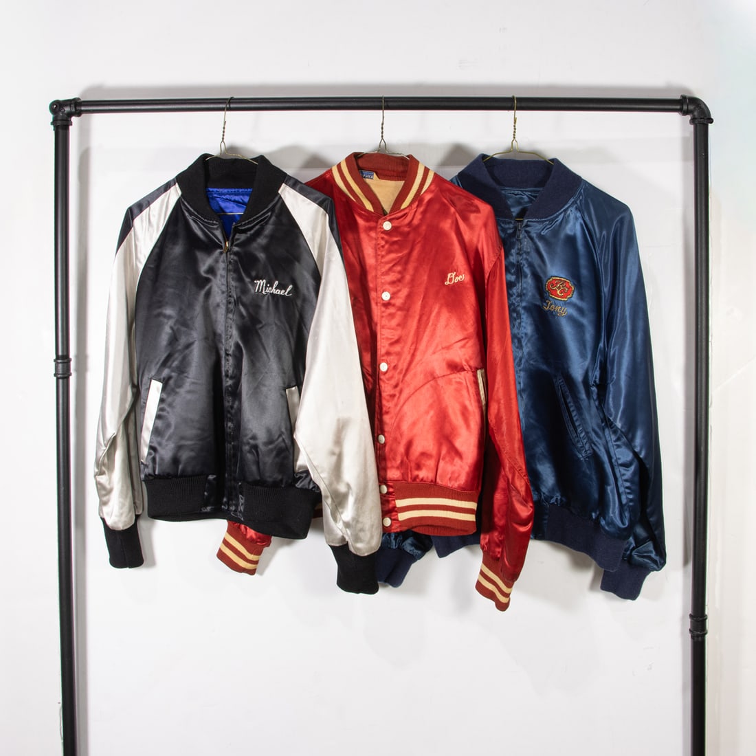 Three vintage satin jackets: Three vintage satin jackets, (1) black "The Beach Boys" size not labeled, (1) navy blue "Barbary Coast" size not labeled, (1) red "BTRY 963 FA BN" size 42