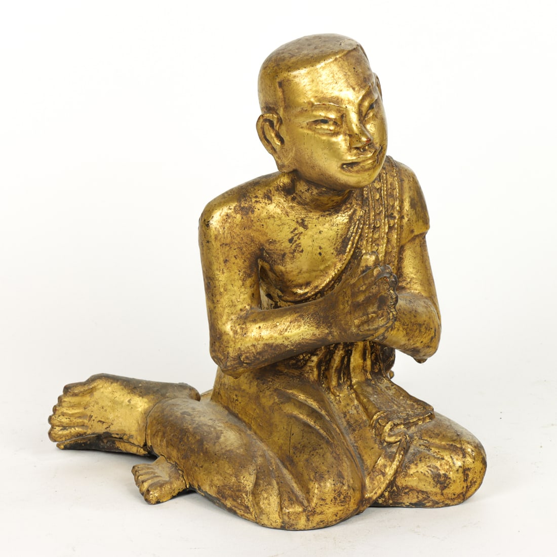 A Thai gilt lacquered wood figure of a Buddhist monk: A Thai gilt lacquered wood figure of a Buddhist monk. 19th century, 9"h x 7.75"w x 8"d.