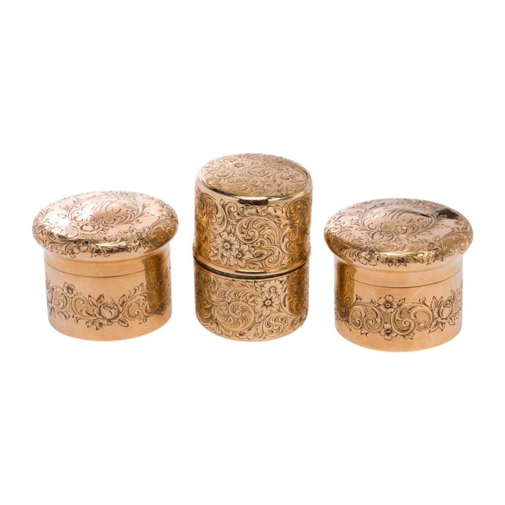 Three Shreve & Co. 14k gold containers: Three Shreve & Co. 14k gold containers each decorated with floral engraving; lengths: 1 - 1/2 in; 54.00 grams