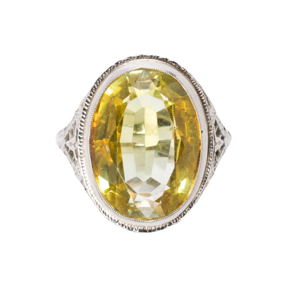 An antique synthetic sapphire and 14k white gold ring: An antique synthetic sapphire and 14k white gold ring The ring of open-form filigree design, set with an oval-cut synthetic sapphire weighing approximately 14.40 carats; size 9; 8.70 grams