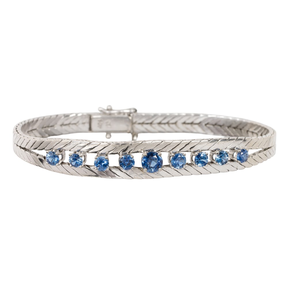 A sapphire and 18k white gold bracelet: A sapphire and 18k white gold bracelet Of herringbone design, set with nine round-cut sapphires weighing approximately 2.00 carats total; length: 7 1/2 in; 30.45 grams