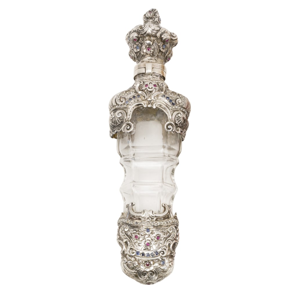 A Continental ruby sapphire and silver mounted glass perfume flask: A Continental ruby sapphire and silver mounted glass perfume flask, 19th century, richly decorated with scrolls, shells and lion heads, 5.5?l. Provenance: The Collection of Irene Deitsch, Palo Alto,