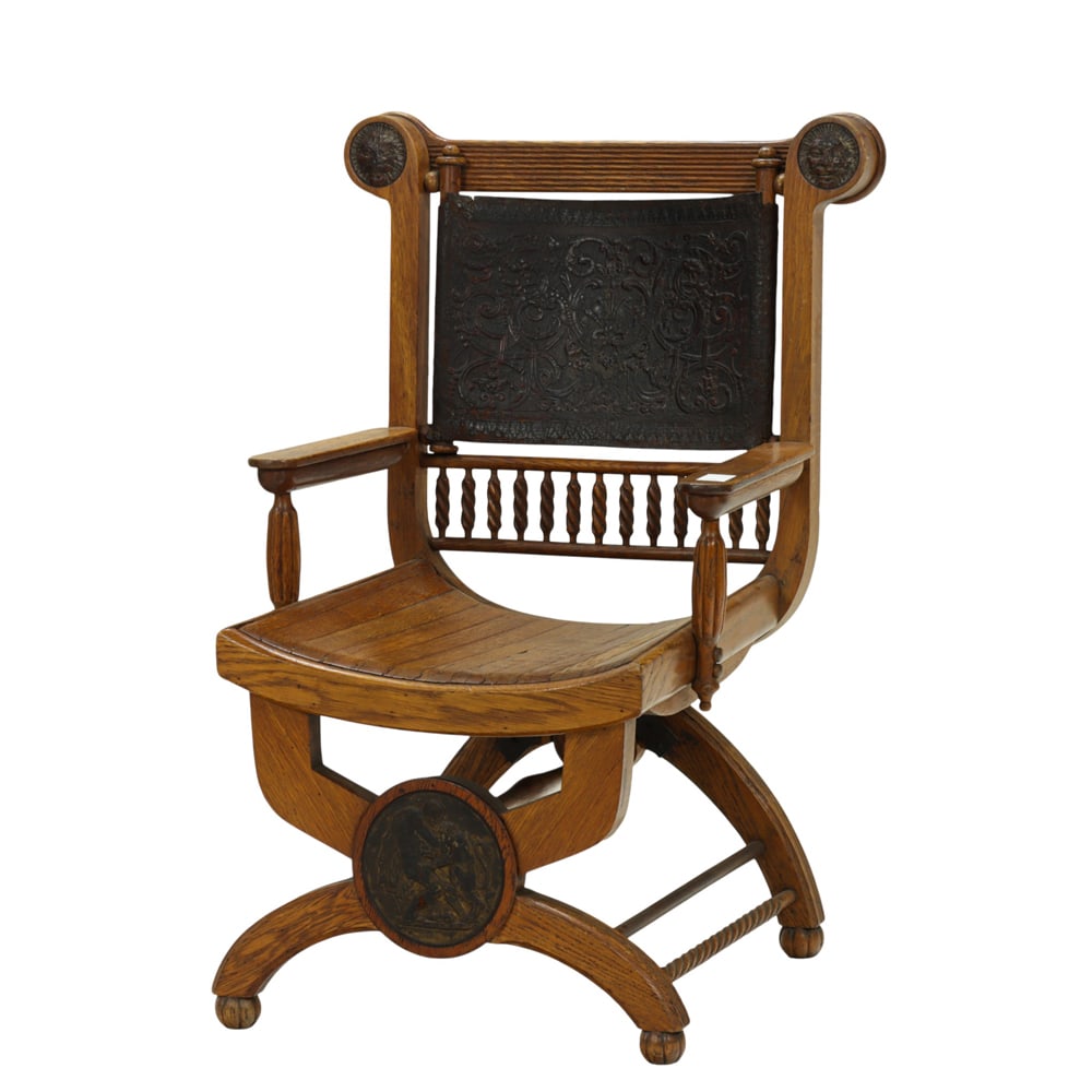 A late Victorian armchair circa 1900: A late Victorian armchair circa 1900, executed in quarter sawn oak, with a leather scenic decorated back support, the deep seat centered with the embossed leather central medallion, and rising on