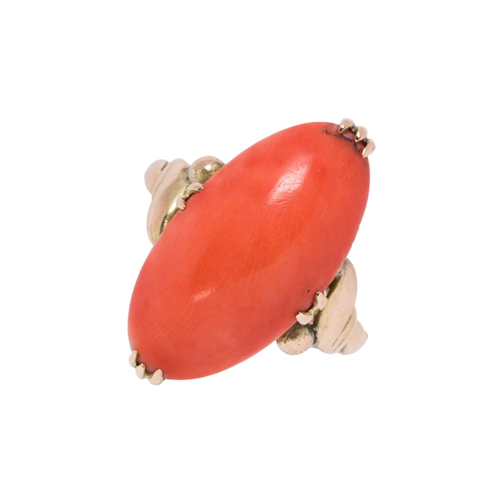 A coral and 18k gold ring: A coral and 18k gold ring centering an oval coral cabochon measuring approximately 18.75 x 10.42 x 4.60 mm; size: 6; 5.10 grams