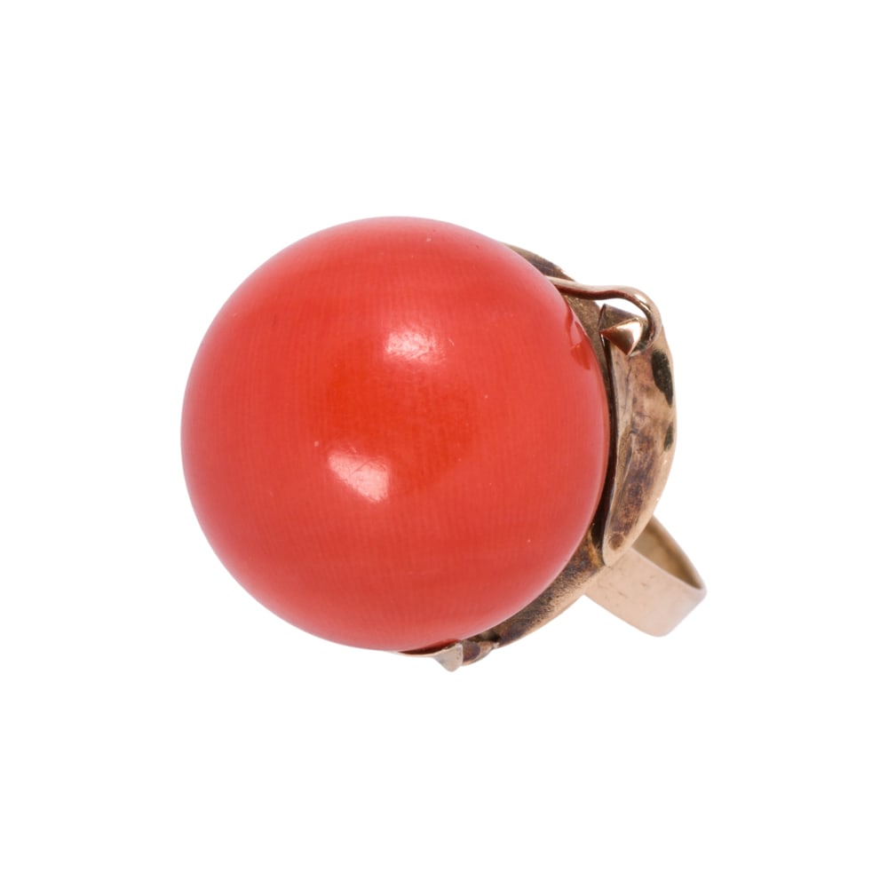 A coral and 18k gold ring: A coral and 18k gold ring centering a coral, bead measuring approximately15.55 mm in diameter; size: 7 1/4 in; 6.40 grams
