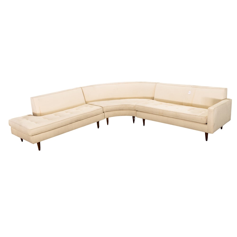 A Mid-Century sectional sofa in three parts: A Mid-Century sectional sofa in three parts, each upholstered in the original textured off white fabric and rising on turned tapered legs, armrest 31"h x 64"w x 33"d; L shaped 31"h x 62"w x 33"d;