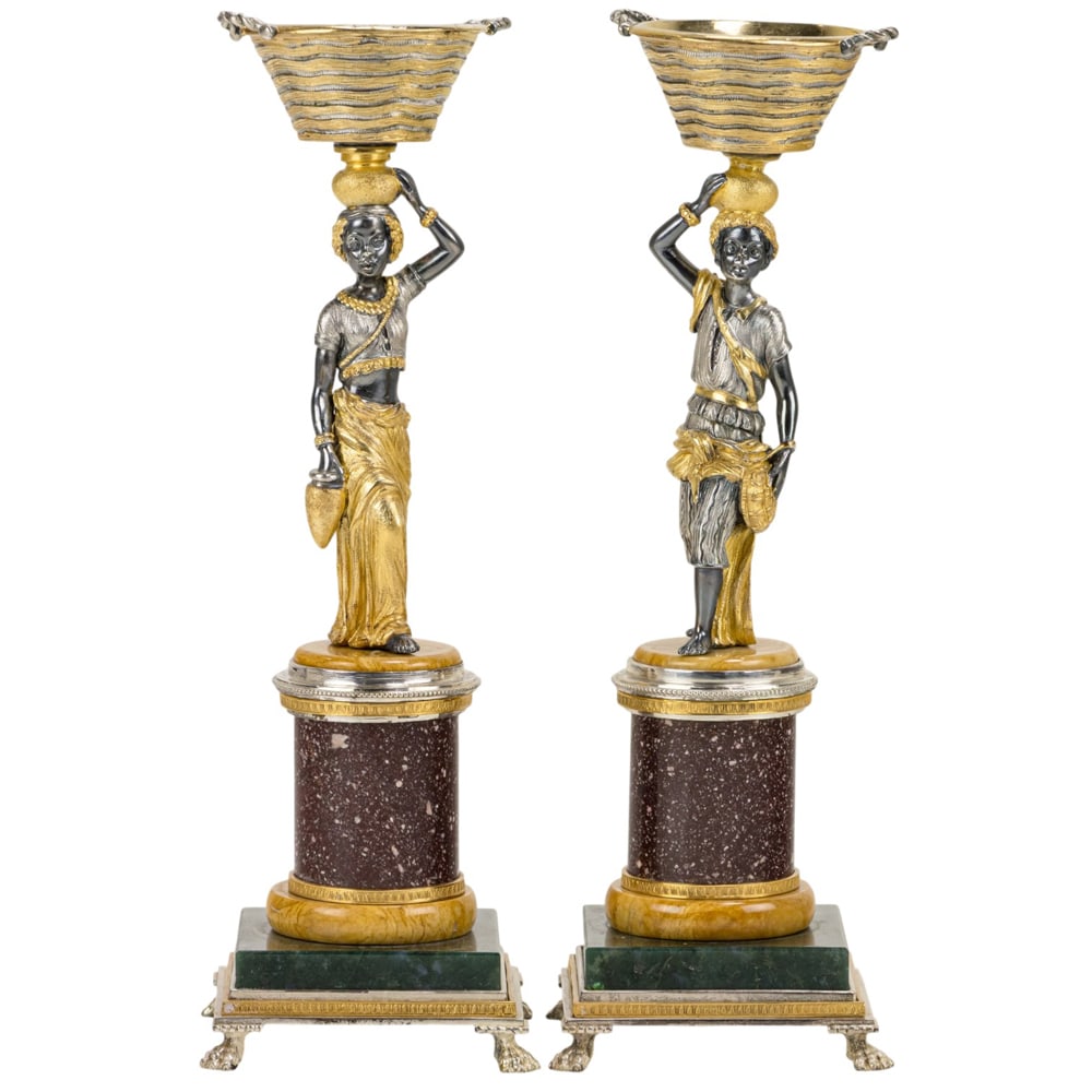 A pair of Attilio Codognato semi-precious stone mounted silver-gilt Venetian figures: A pair of Attilio Codognato semi-precious stone mounted silver-gilt Venetian figures, each figure carrying a basket on its head and raised on a pedestal plinth with possibly Giallo Antico, porphyry an