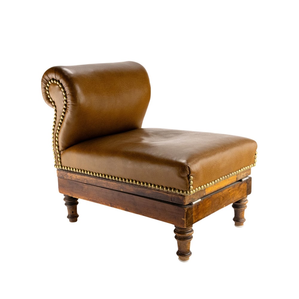 An Edwardian gout stool: An Edwardian gout stool, with leather upholstery and brass nail head trim, and rising on turned legs, extended 27"h x 12.5"w x 22"d, closed 17"h x 12"w x 18"d