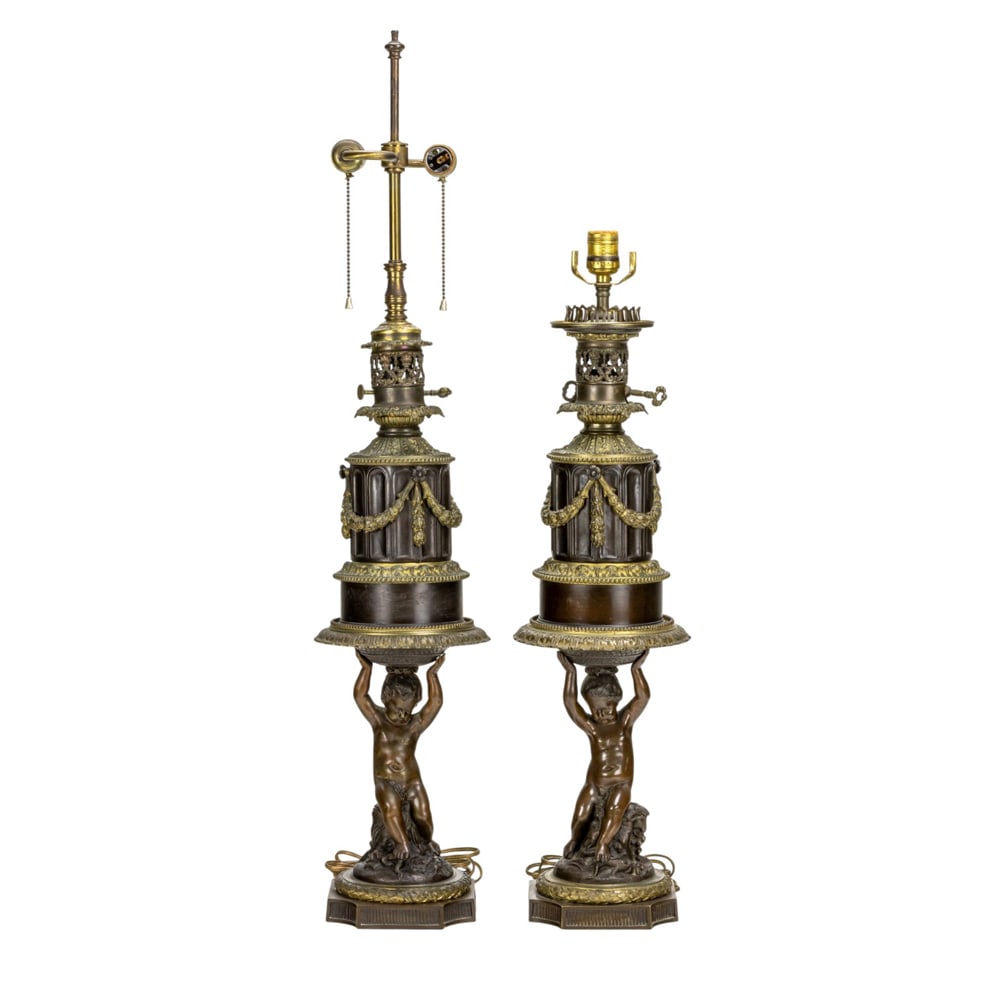 A pair of French patinated and gilt bronze oil lamps: A pair of French patinated and gilt bronze oil lamps, now mounted with electrical fittings, Lampe Aureole, Paris, second half 19th century, each modeled as an infant putto holding aloft a columnar for