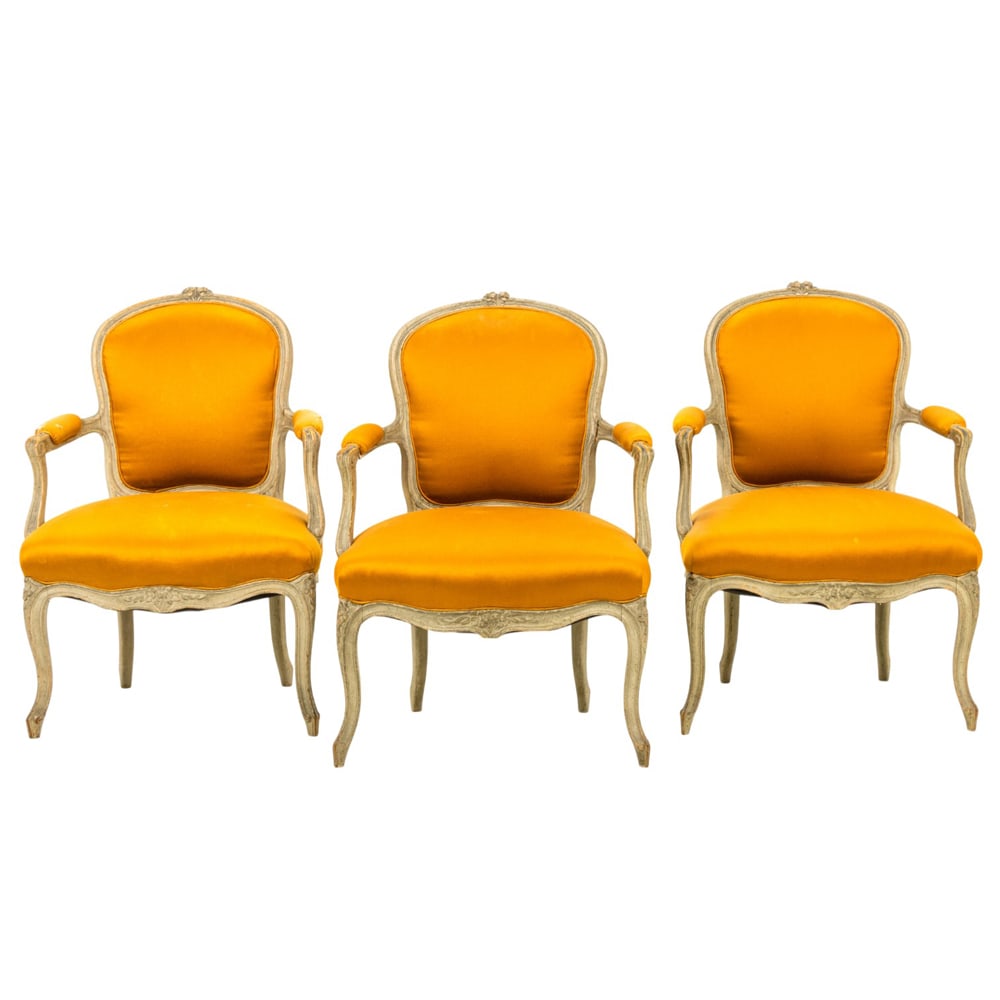 A group of three Louis XV style armchairs: A group of three Louis XV style armchairs, each with a polychrome frame and poppy upholstery, rising on floral carved cabriole legs, 34"h x 23.5"w x 20" (overall); 19"h x 19.5"d (seat)