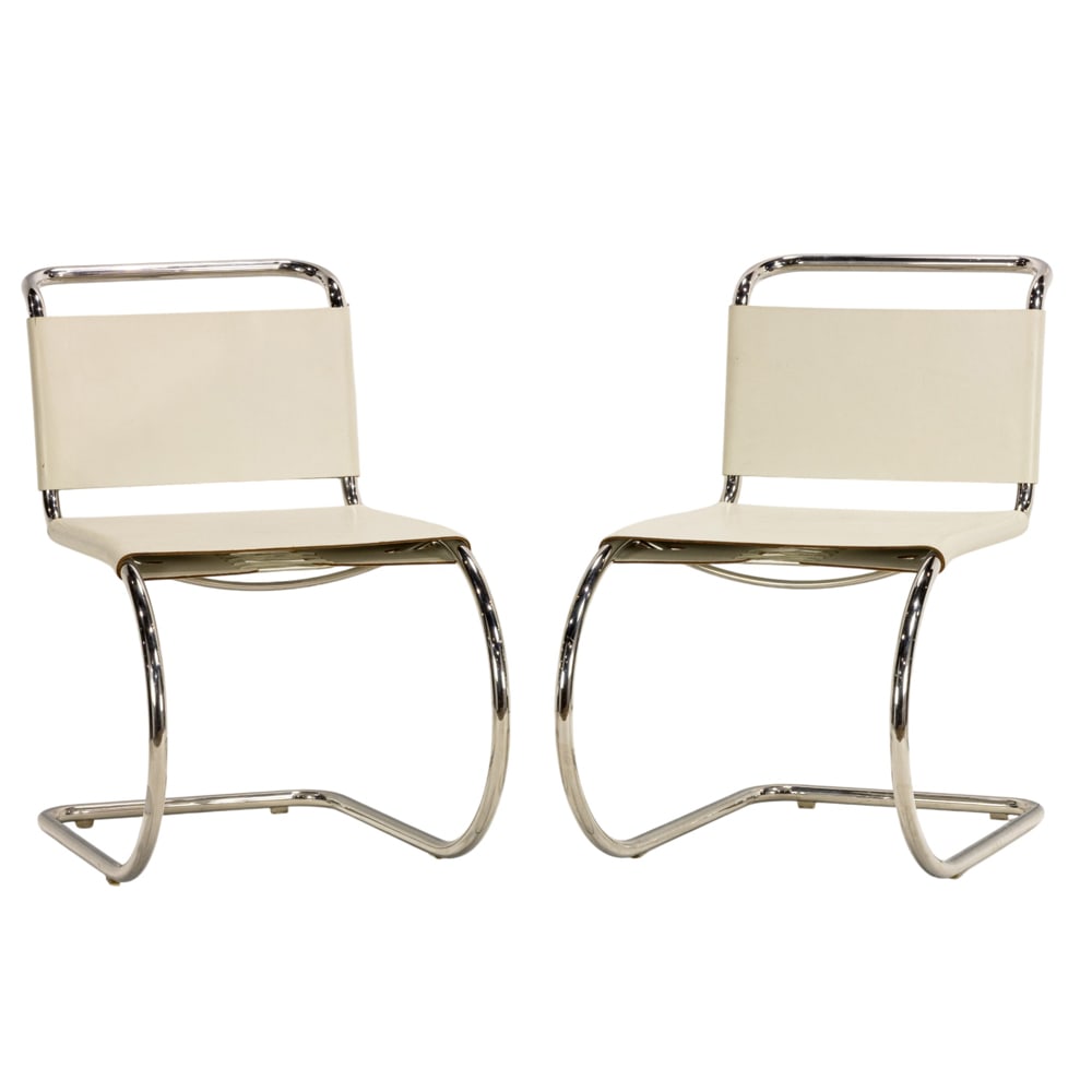 A pair of Mies van der Rohe MR10 white leather chairs: A pair of Mies van der Rohe MR10 white leather chairs, each with a tubular cantilevered frame and white leather sling seat and back, 31"h x 19"w x 26"d (overall); 18"h x 14"d (seat)