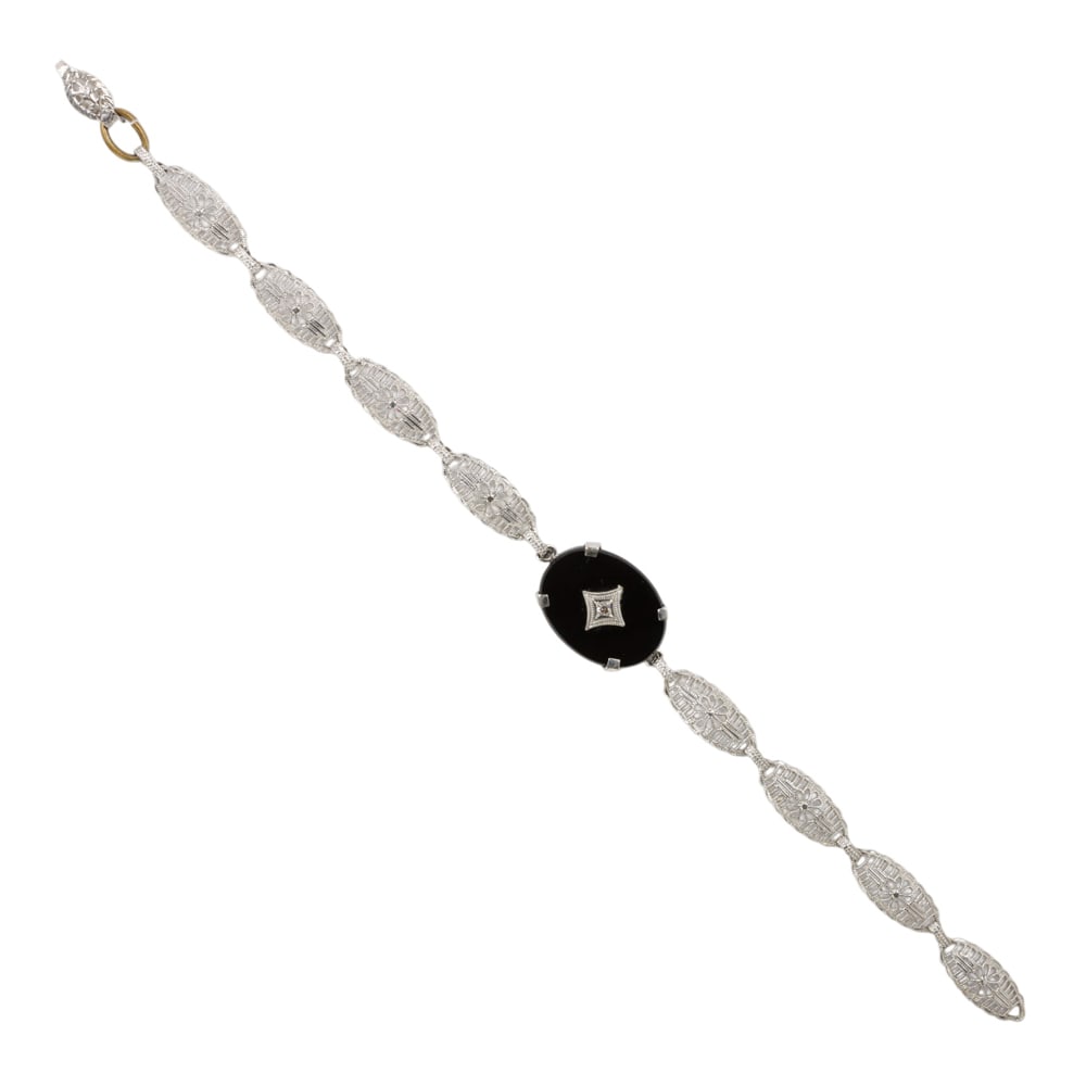 An antique onyx, diamond and 10k white gold bracelet: An antique onyx, diamond and 10k white gold bracelet the filigree link bracelet centering an oval-shaped onyx centered by a round-cut diamond; length: 6 1/4 in; 2.91 grams (one jump ring not gold)