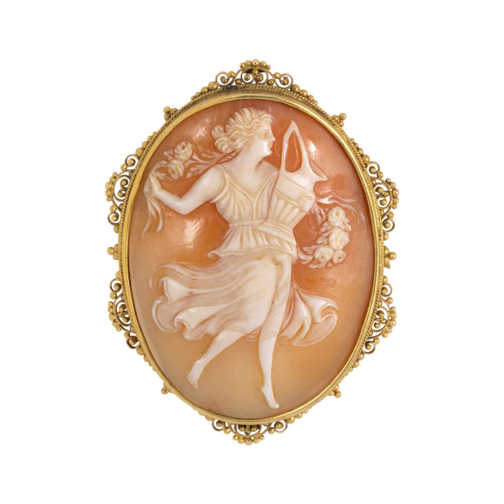 A cameo and 18k gold brooch: A cameo and 18k gold brooch centering a carved shell cameo measuring approximately 38.00 x 30.50 mm, within filigree gold frame; length: 2 3/4 in; 11.10 grams