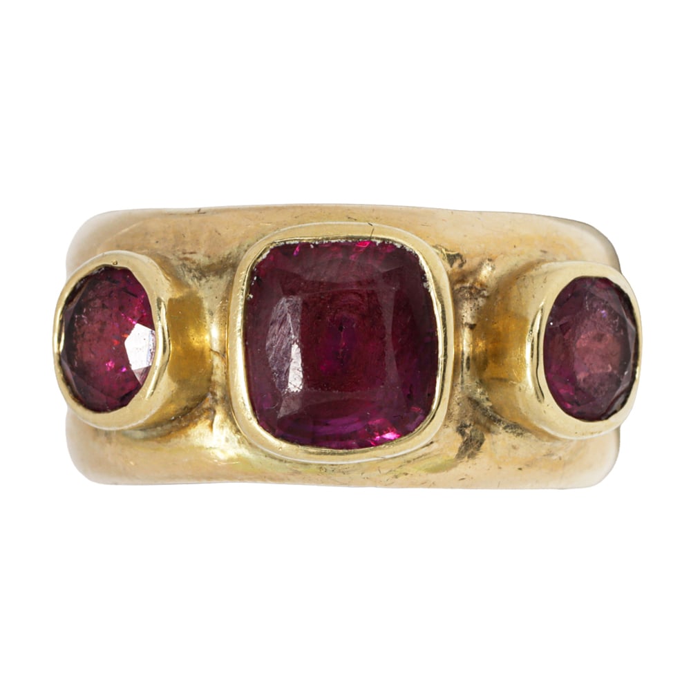 A rhodolite garnet and 14k gold ring: A rhodolite garnet and 14k gold ring The ring set with one cushion-cut rhodolite garnet measuring 6.80 x 6.24 x 4.77 mm, framed on either side by one round-cut rhodolite garnet measuring 4.79 x 4.79