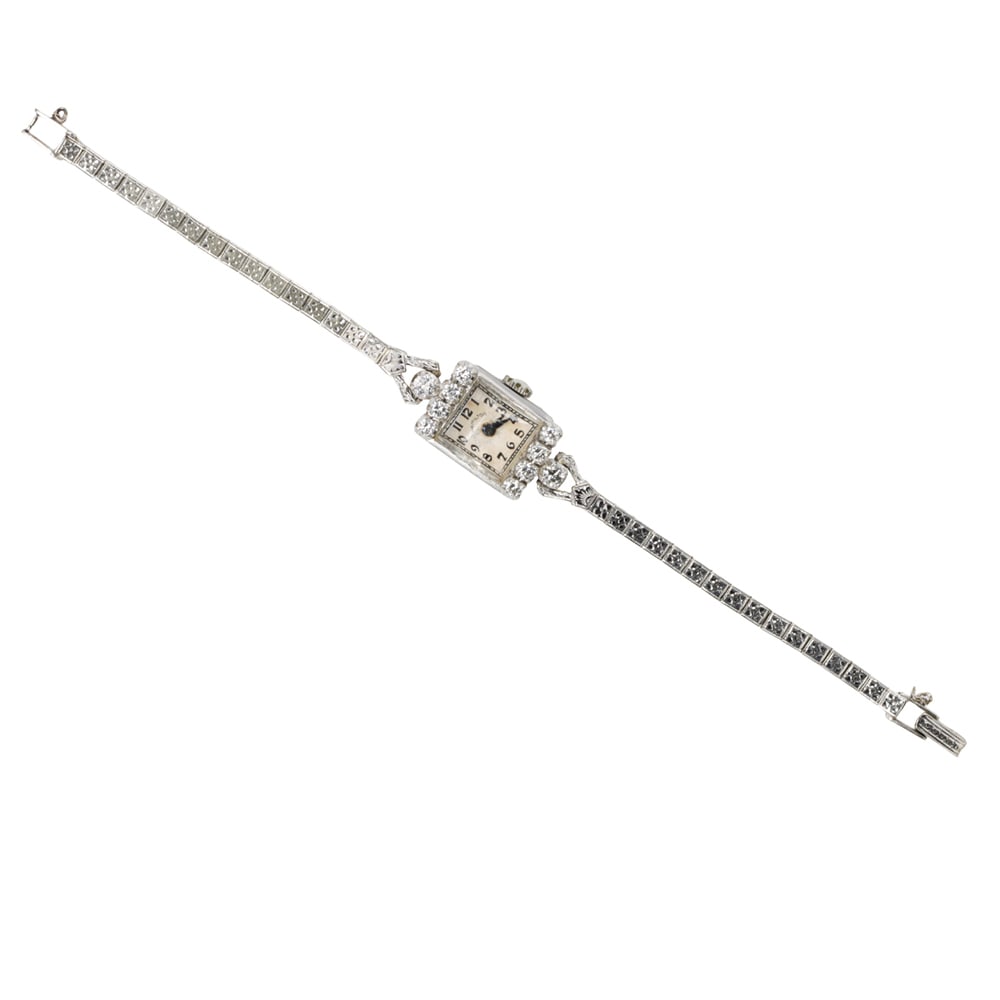 A Hamilton diamond, platinum, and 14k white gold watch: A Hamilton diamond, platinum, and 14k white gold watch The white-tone face, black Arabic indices, blue lance hands, within polished platinum case set with ten round brilliant-cut diamonds, containing 