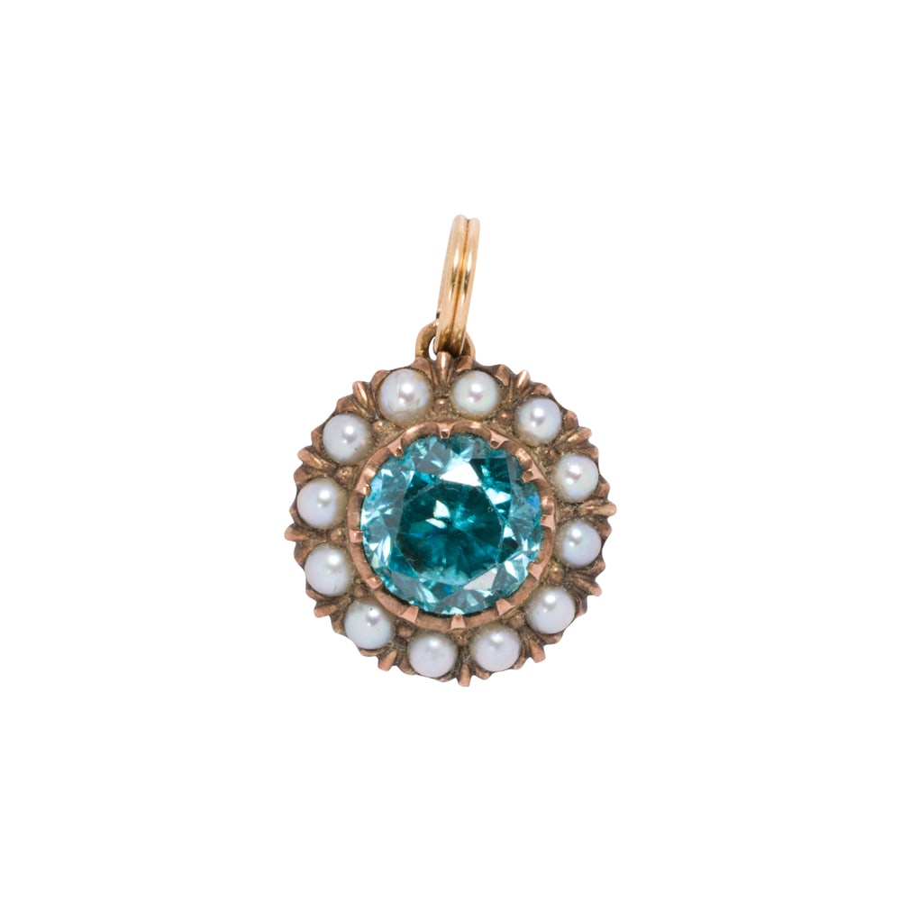 An antique blue zircon, seed pearl, and gold-filled pendant: An antique blue zircon, seed pearl, and gold-filled pendant Centering a round-cut blue zircon weighing approximately 2.70 carats, with seed pearl surround; length: 3/4 in; 3.90 grams