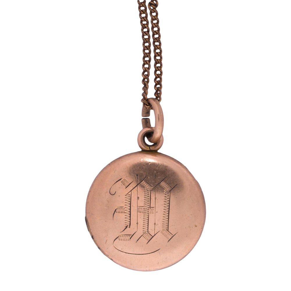 An antique gold-filled locket necklace: An antique gold-filled locket necklace Featuring a round shaped locket monogrammed with the letter "M"; locket length: 1 in; chain length: 18 in; 5.00 grams