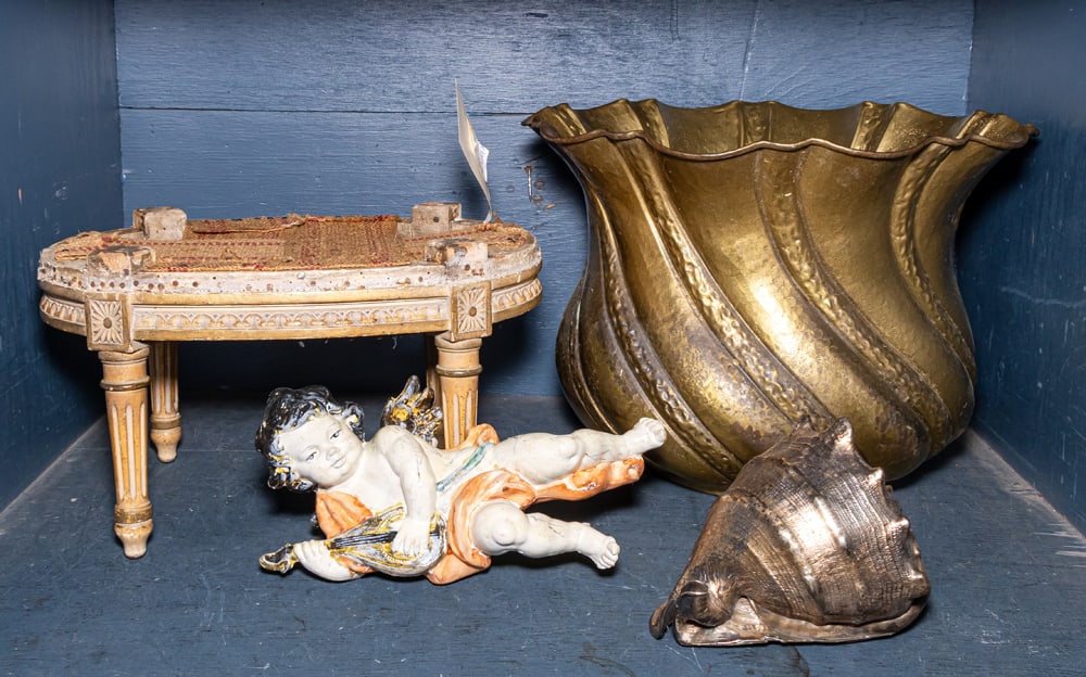 An assembled group of mostly house decor: An assembled group of mostly house decor, comprising (1) metal cased conch shell, (1) brass repousse jardiniere, 11.5"h x 15"dia, (1) foot stool frame, and (1) figure of a putto, 10.5"l [4 total]
