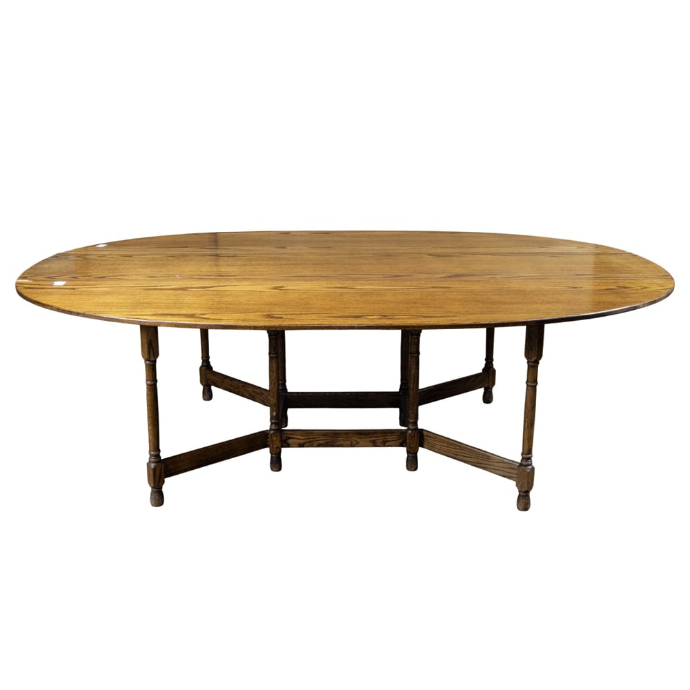 An English style oak drop-leaf oval dining table: An English style oak drop-leaf oval dining table, raised on turned gate leg supports joined by stretchers, 29"h x 94"w x 59"d (greatest); 19"d (folded)
