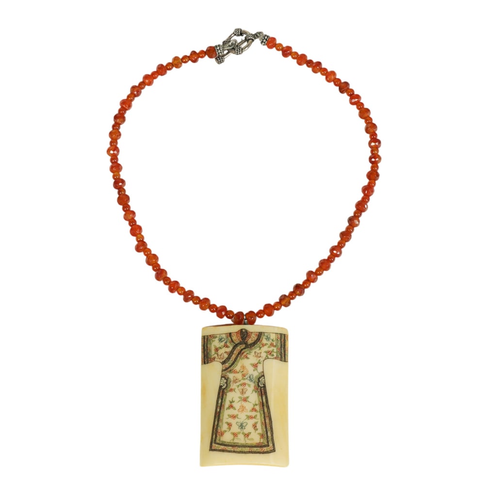 A carnelian necklace with bone pendant: A carnelian necklace with bone pendant. Depicting a Chinese robe motif, 18.5" long.