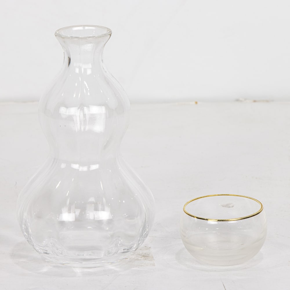 A Japanese boxed crystal sake set: A Japanese boxed crystal sake set, comprising two fluted gourd form Sake decanters and ten cups with incised hatch mark frosted bases