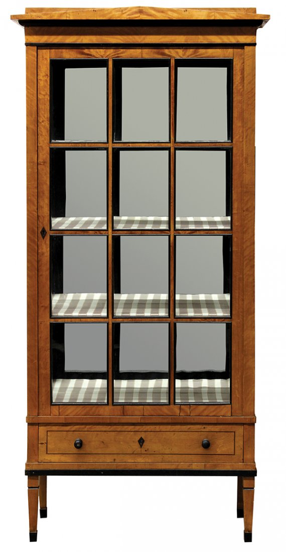 Continental partially ebonized Biedermeier vitrine: Biedermeier vitrine, 19th century, having a peaked crest above a glazed and mullioned door with ebonized escutcheon opening to lined shelves, surmounting the single drawer and rising on tapered legs t