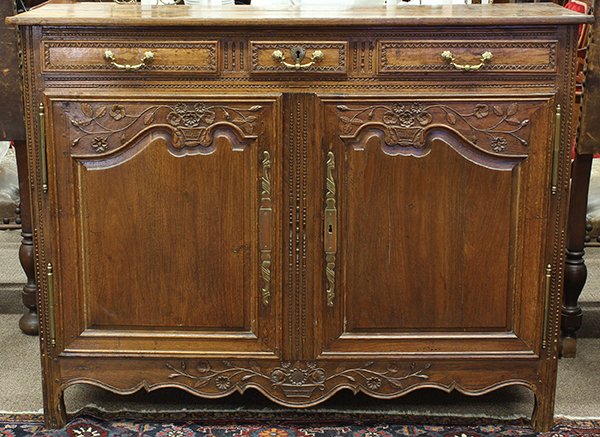 French Provincial style oak buffet: French Provincial style oak buffet, circa 1800, the rectangular top above a panelled case accented with floral sprays and rising on carved legs conjoined by the carved and scalloped apron, 42.5"h x 55