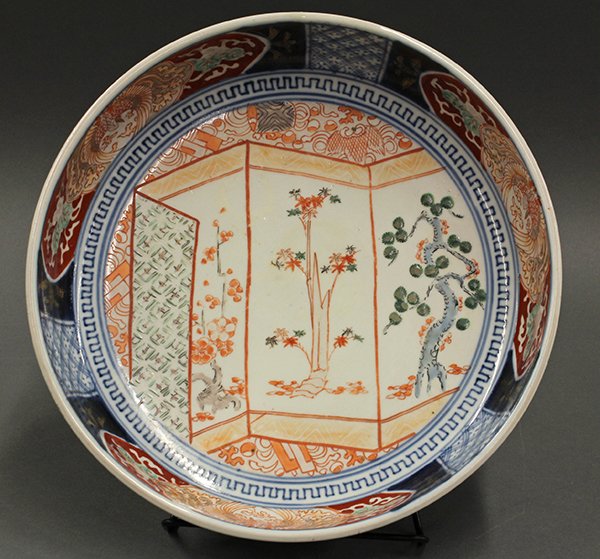 Japanese Imari Bowl, 19c: Japanese Imari porcelain bowl, late Edo/Meiji period, the well decorated with a screen featuring pine, maple and plum blossoms, the interior sides accented with phoenix reserves, 11"dia