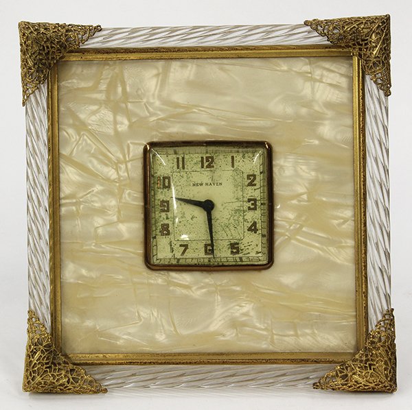 Art Deco style New Haven table clock: Art Deco table clock by New Haven, having Arabic markers flanking the original dial, within a frame having gilt decorated corner mounts conjoining the clear twist border, 6.75"w x 6.75"h