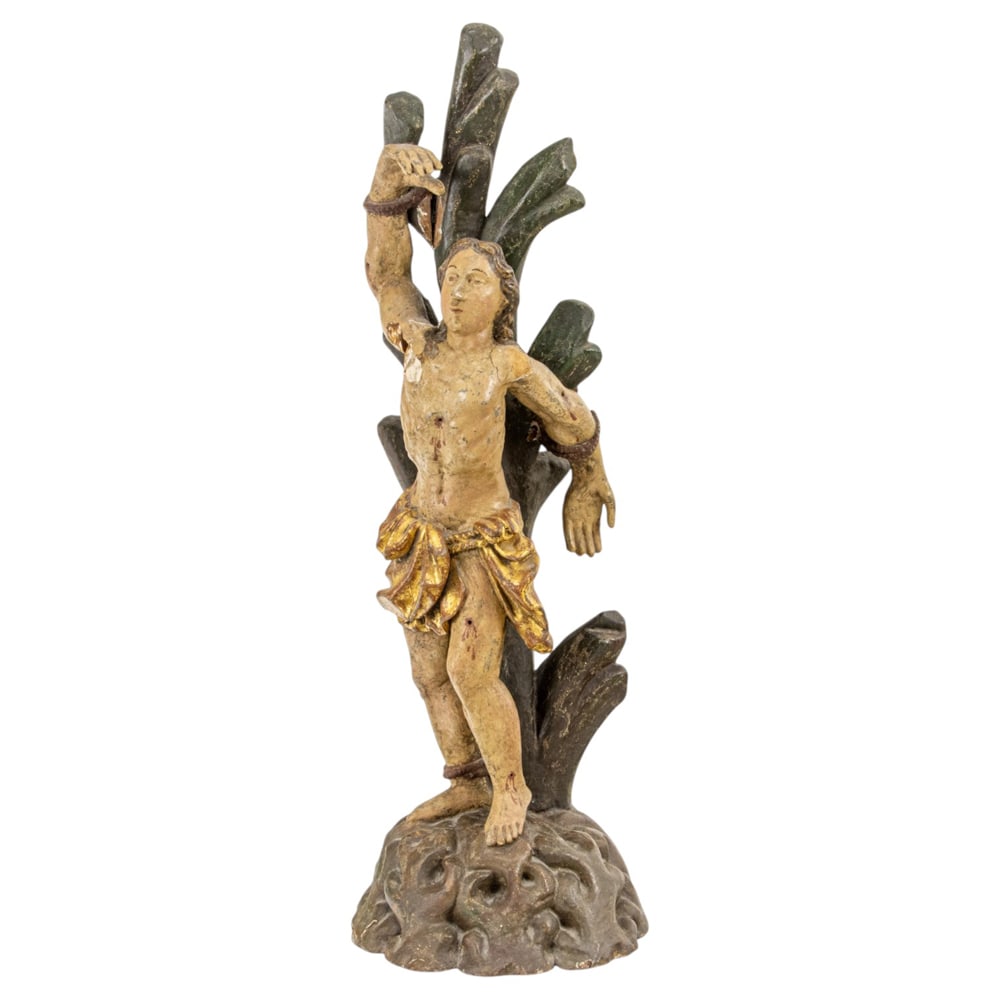 A Colonial polychrome and parcel gilt figure of Saint Sebastian: A Colonial polychrome and parcel gilt figure of Saint Sebastian, 18th century, depicted bound to a tree, and standing on rocky outcrop, 26.5"h x 9"w x 8.5"d