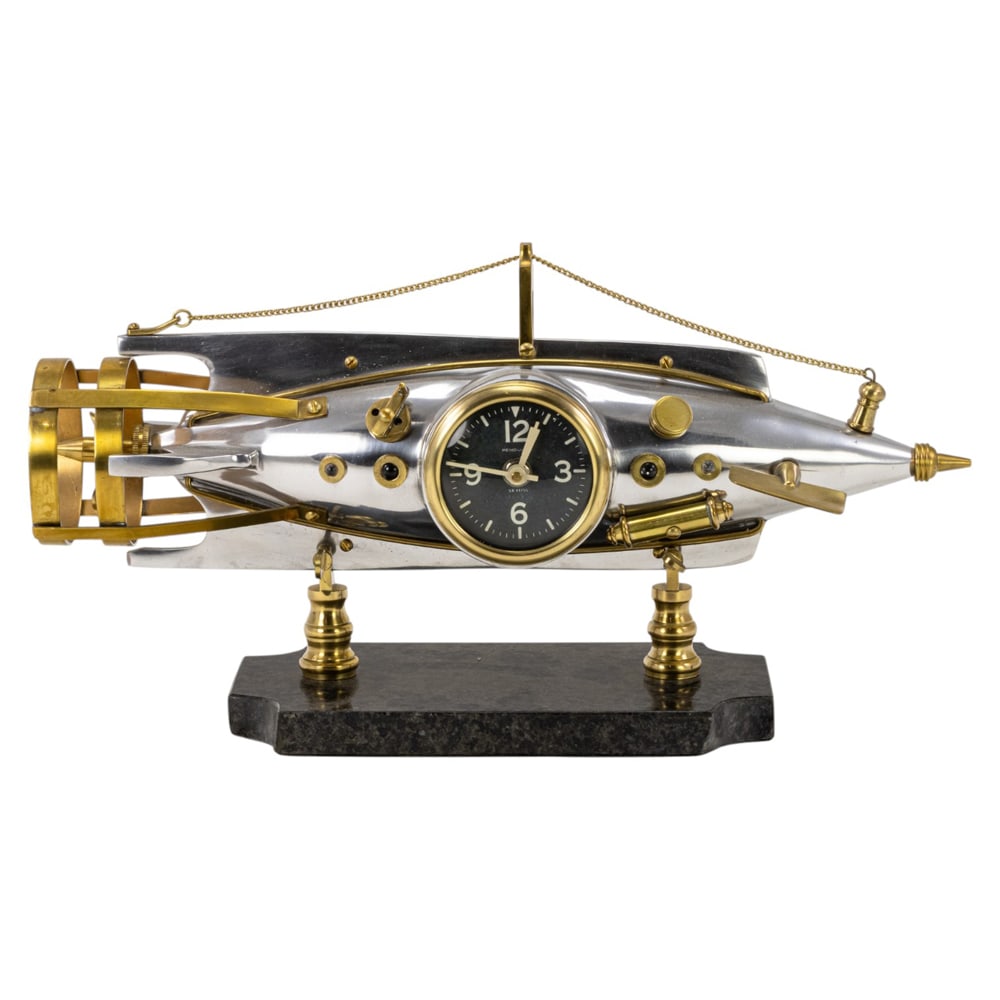 A Pendulux Nautilus aluminum and brass table clock: A Pendulux Nautilus aluminum and brass table clock, in the form of a torpedo with moveable propeller and drive planes, fitted with battery movement, raised on marble plinth, 9"h x 17.5"w x 6"d