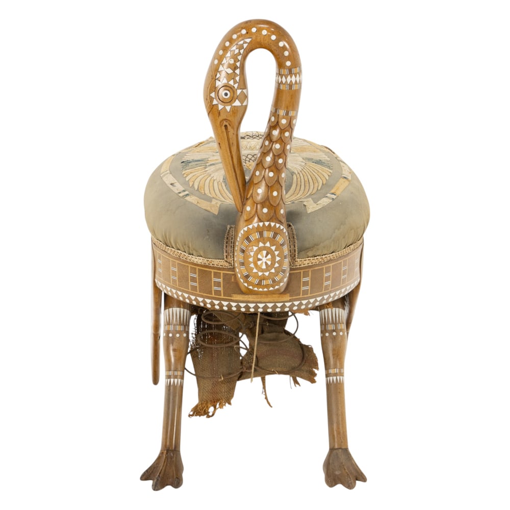 An Egyptian Revival ibis stool third quarter 19th century: An Egyptian Revival ibis stool third quarter 19th century, the inlaid back continuing to the original upholstered show cover depicting a winged Egyptian deity, and resting on wing and talon legs,