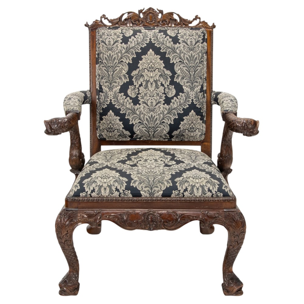 A Georgian style carved armchair: A Georgian style carved armchair, the highly carved form with fish-scaled scrolling arm rests continuing to the seat rail, and rising on stylized fish form legs, 41"h x 33"w x 22"d (overall); 18.5"h