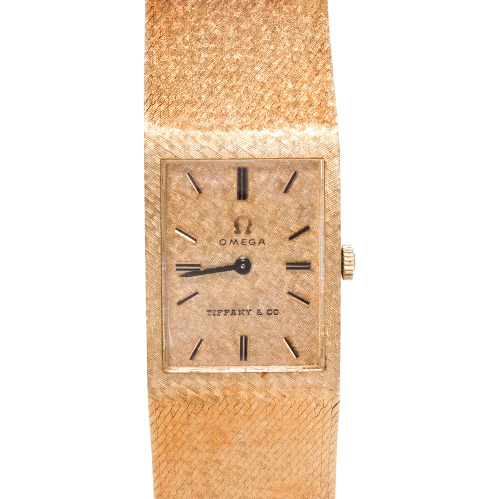A Omega for Tiffany & Co. 14k gold watch: A Omega for Tiffany & Co. 14k gold watch Ref no.: D6751Case no: 142253Movement no. 27423970The textured gold dial with gold baton hours and black baton hands, within attached watch bracelet case conta