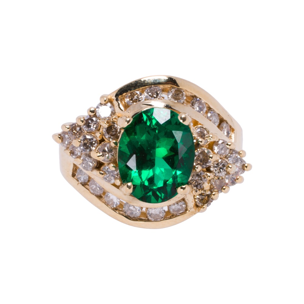 A synthetic emerald, diamond, and 14k gold ring: A synthetic emerald, diamond, and 14k gold ring Centering an oval-cut synthetic emerald weighing approximately 2.50 carats, framed within an arrangement of 30 round brilliant-cut diamonds; estimated