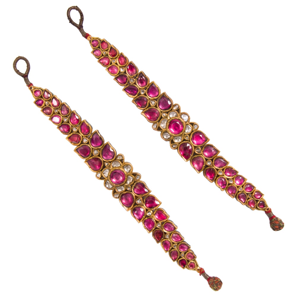 A pair of South Asian ruby, diamond, and high karat gold bracelets: A pair of South Asian ruby, diamond, and high karat gold bracelets Each featuring numerous foil backed rubies and diamonds, the verso inscribed with intricate enamel detail; length: 7 3/8 in; gross