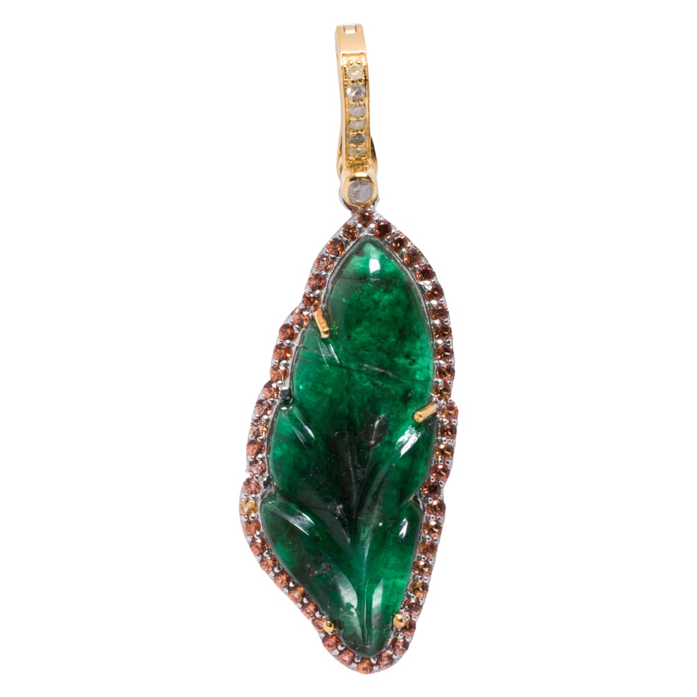 An emerald, sapphire, diamond, silver, and 14k gold pendant: An emerald, sapphire, diamond, silver, and 14k gold pendant The silver pendant set with a carved emerald feather weighing 8.09 carats, framed by round-cut sapphires, on diamond-set 14k gold bail;