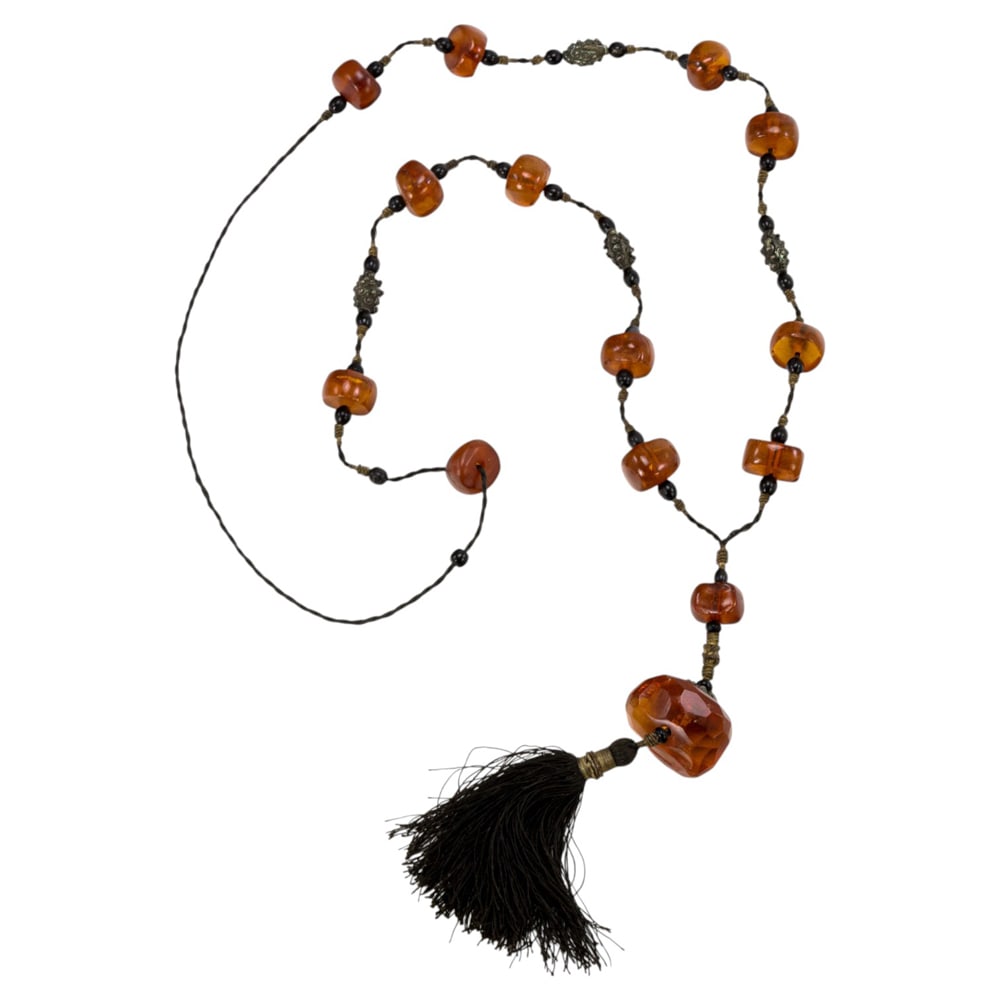 A Chinese amber bead necklace: A Chinese amber bead necklace. Comprising 14 amber beads, early 20th century, 49"long.