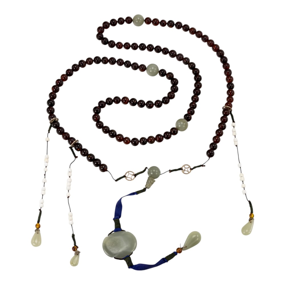 A Chinese amber and jade court necklace: A Chinese amber and jade court necklace. Comprising 108 amber beads and four jade beads, early 20th century, 65" long.