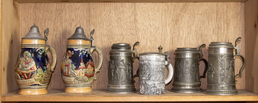 A group of six German steins: A group of six German steins, including (3) pewter steins; pair of pottery 1 liter steins and (1) porcelain stein, between 5.5"h and 9.5"h