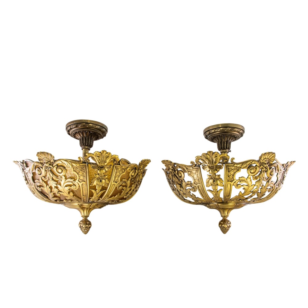 A pair of brass and glass pendant fixtures: A pair of brass and glass pendant fixtures, each cast with leaves and lined with opaque or amber glass, enclosing three lights, one mount with label for 'Sterling Bronze Company, New York', shade: 6.2