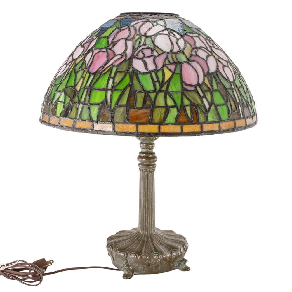 An Arts and Craft style leaded glass lamp: An Arts and Craft style leaded glass lamp, with a floral decorated shade above the patinated metal shade,19"h x 15.5"dia (shade)